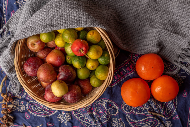 Muchos colores y variedades de fruta están en el plato o dispersos en la mesa de madera - Foto, Imagen