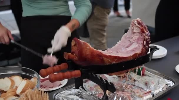 Een vrouw die Italiaanse ham snijdt, bekend als prosciutto cotto met een hammes. en leg de plakjes op de plaat - Video