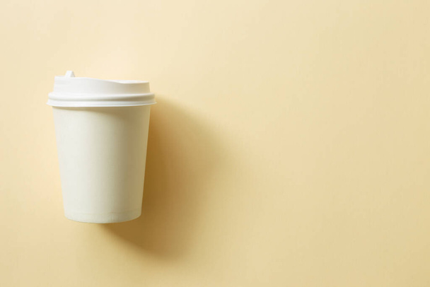 Papel branco xícara de café no fundo bege. vista superior, espaço de cópia - Foto, Imagem
