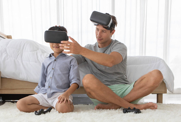 Батько і його син змішаної раси в пристрої віртуальної реальності vr, щоб грати в гру разом з весело і щасливо в спальні
 - Фото, зображення