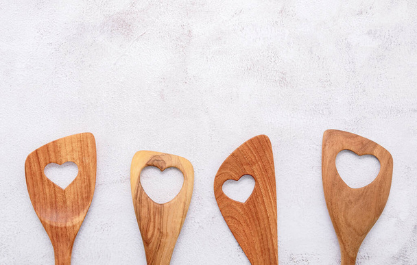 Varie forma di cuore di utensili da cucina in legno. Cucchiai di legno e spatola di legno su sfondo di cemento bianco con posa piatta e spazio copia. - Foto, immagini