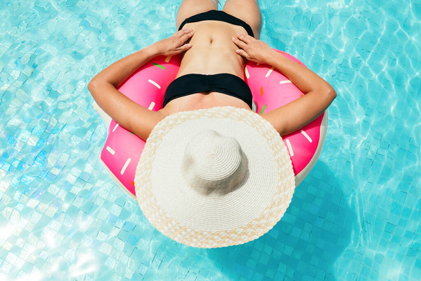 Enjoying suntan woman in bikini on the inflatable mattress - Фото, изображение