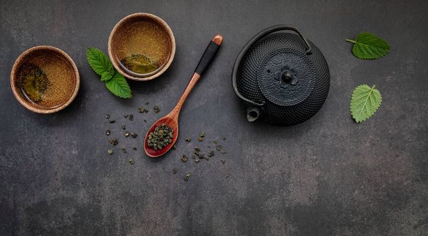 Panela de chá de ferro fundido preto com chá de ervas configurado no fundo de pedra escura. - Foto, Imagem