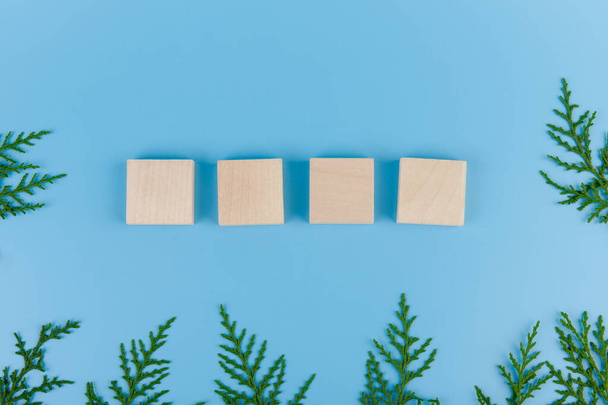 Vier Holzblöcke mit Zypressenzweigen auf blauem Hintergrund für Ihr Design. Das Konzept des neuen Jahres, Weihnachten. - Foto, Bild