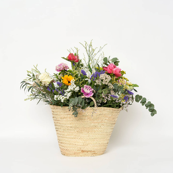A beautiful bouquet in a wicker bag isolated on a white background - Foto, afbeelding