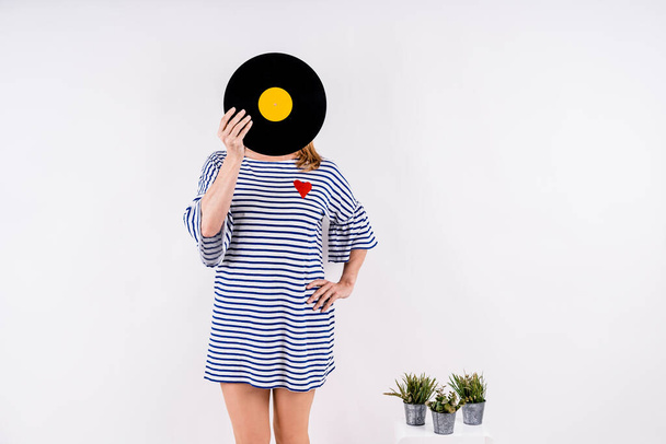 A sexy Caucasian woman keeps a vinyl on a white background - Foto, Bild