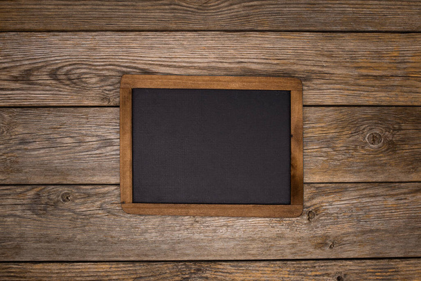 A black empty frame with copy space on a wooden surface - Фото, изображение