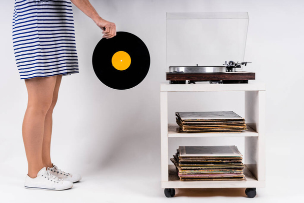 A sexy Caucasian woman keeps a vinyl on a white background - Foto, Imagen