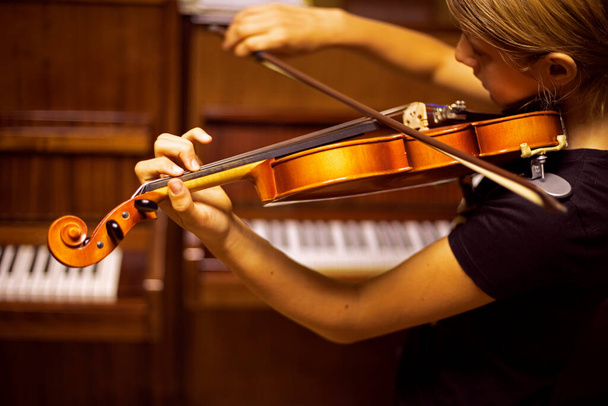 junger Geiger musiziert auf der Geige mit dem Rücken in Klaviernähe, waagerecht - Foto, Bild