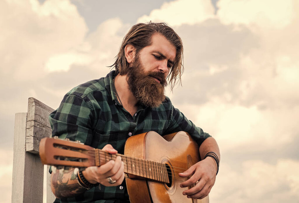 become popular. music performer musician. musical string instrument. mature charismatic male guitarist. guy with beard and moustache play guitar. bearded man in checkered shirt sing song - Photo, Image
