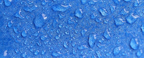 Water drops on the fabric. Rain Water droplets on blue fiber waterproof fabric. Water drops pattern over a waterproof cloth. Blue background. - Photo, Image