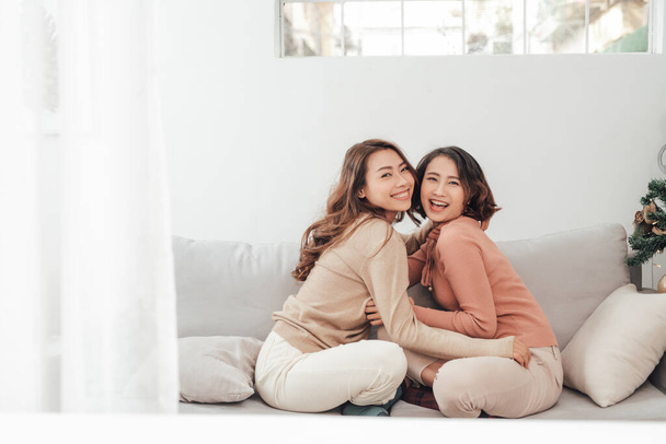Dva happy přátelé nebo sestry objímání na gauči v obývacím pokoji doma - Fotografie, Obrázek
