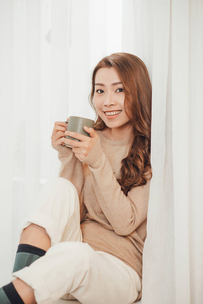 Young woman with cup of hot tea basking on xmas holidays. - Photo, Image