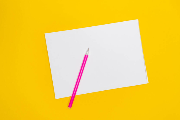 メモ帳は黄色の背景にピンクのペンでコピースペースのための場所.  - 写真・画像