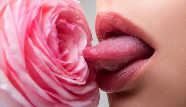 Lips with tongue closeup. Beautiful woman lips with rose. Sexy lips. Macro of womans face part. Sexy glossy lip makeup. Beauty red lip makeup detail. - Valokuva, kuva