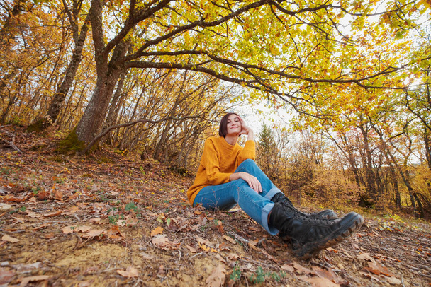 Kobieta turystyka patrząc na malowniczy widok jesiennego krajobrazu górskiego liści. Outdoor przygoda podróży pani siedzi relaks w przyrodzie w sezonie jesiennym. - Zdjęcie, obraz