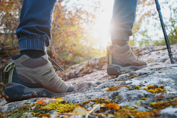 trekking męskie buty zbliżenie, człowiek wspina się po górach przez jesienny las podczas zachodu słońca. koncepcja podróży i turystyki pieszej. - Zdjęcie, obraz