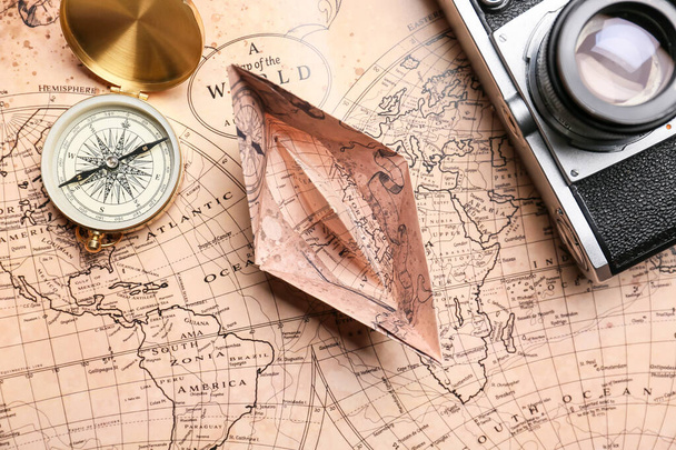 Barco de papel, bússola, câmera fotográfica e mapa do mundo, close-up - Foto, Imagem