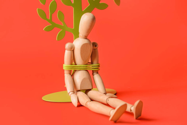 Mannequin avec attaché autour de la corde près de l'arbre sur fond de couleur. Concept d'otage - Photo, image