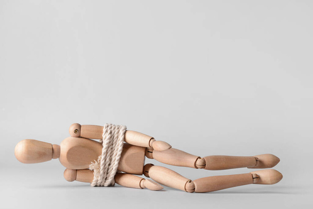 Mannequin with tied around rope on grey background. Concept of hostage - Fotó, kép