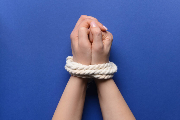 Female hands with tied around rope on color background. Concept of hostage - Fotografie, Obrázek