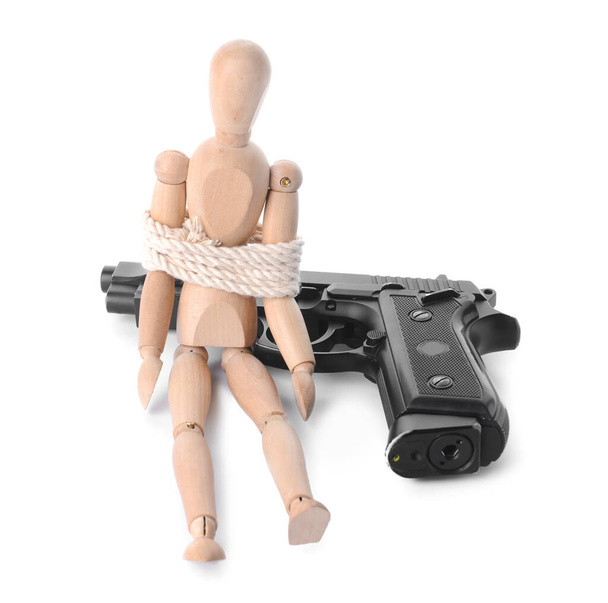 Пистолет и манекен с привязанной веревкой на белом фоне. Концепция заложника - Фото, изображение