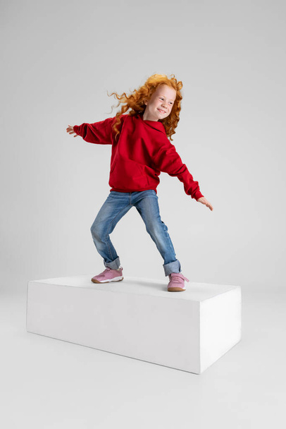 Portrait of little girl, child standing in pose of surfer isolated over gray studio background. - Fotó, kép