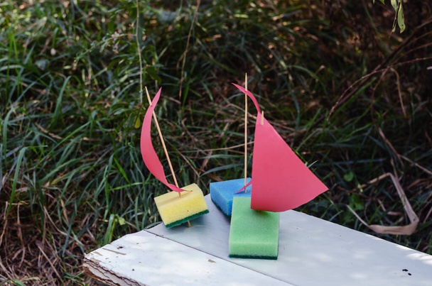 Tres barcos de juguete caseros en un banco del parque blanco. Velero de niños - Foto, imagen