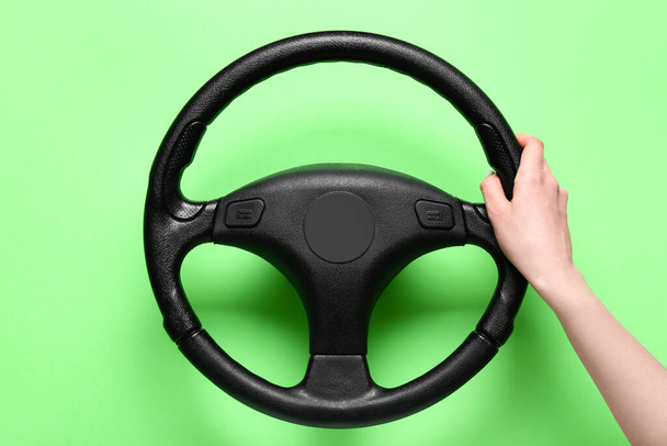 Female hand and steering wheel on green background - Photo, Image