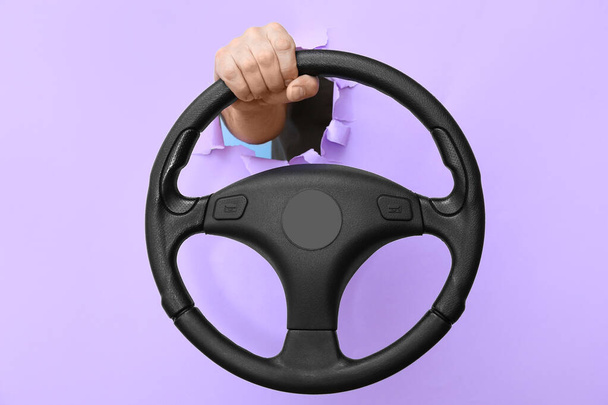 Man holding steering wheel through hole in color paper - Photo, Image