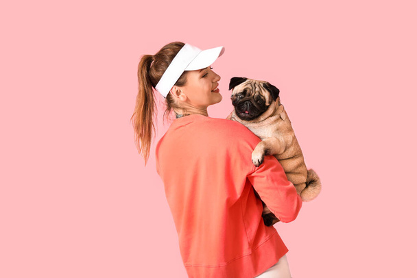Jeune femme tenant chiot mignon chien sur fond rose - Photo, image