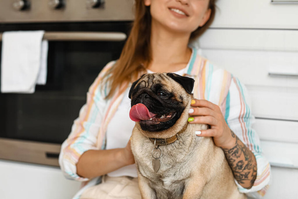 Young woman with cute pug dog in kitchen - Photo, Image
