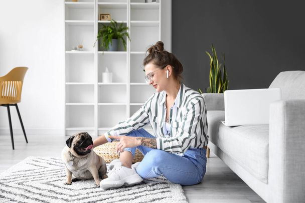 Young woman with cute pug dog sitting on floor at home - Photo, Image