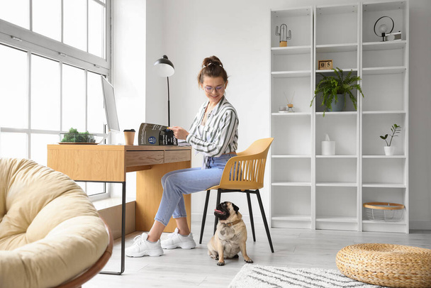 Young woman with cute pug dog reading magazine at home - Foto, Imagen