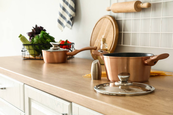 Copper cooking pot with saltcellar on counter in kitchen - Фото, зображення