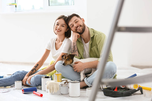 Young couple with cute dog resting during repair of their new house - Foto, imagen