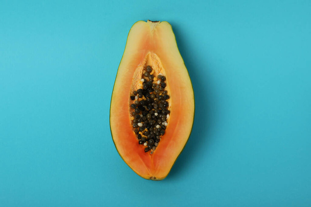 Половина спелой папайи на синем фоне - Фото, изображение