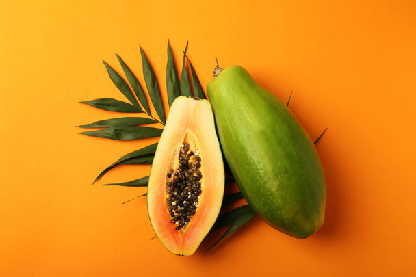Ripe papaya με φύλλα σε πορτοκαλί φόντο - Φωτογραφία, εικόνα