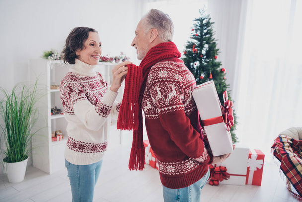 Photo of shiny charming age couple dressed print pullovers presenting gifts smiling indoors room home house - Photo, Image