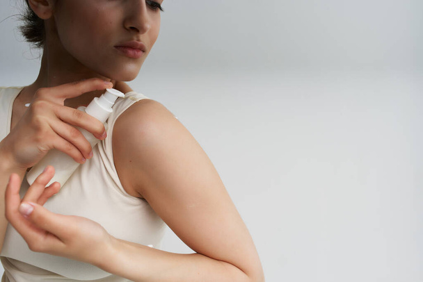 mujer en camiseta blanca aplica crema a la piel de cerca - Foto, imagen