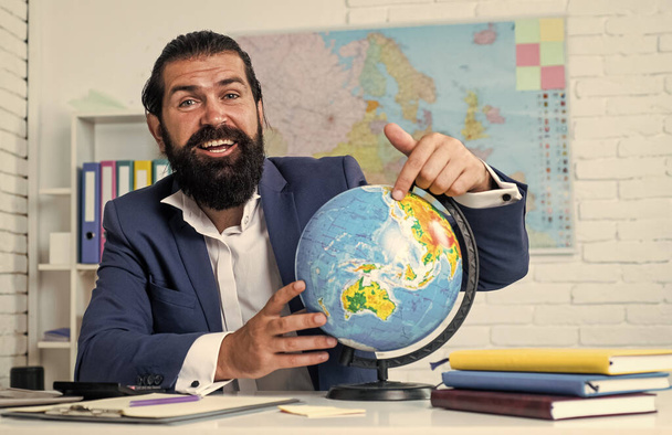 geography studying. informal education. male student sit in school classroom with map. pass the exam. learning the subject. geographer. happy man with beard pointing at globe - Foto, Imagem