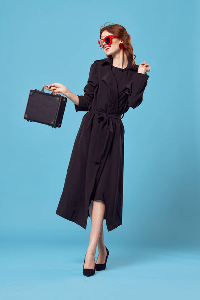 Donna d'affari in cappotto nero indossare occhiali da sole camminare sfondo blu - Foto, immagini