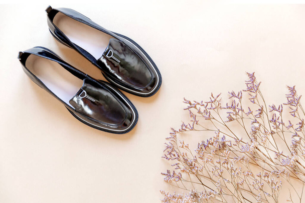 Μοντέρνα μινιμαλιστική σύνθεση, γυναικεία μαύρα παπούτσια με αποξηραμένα λουλούδια.  - Φωτογραφία, εικόνα