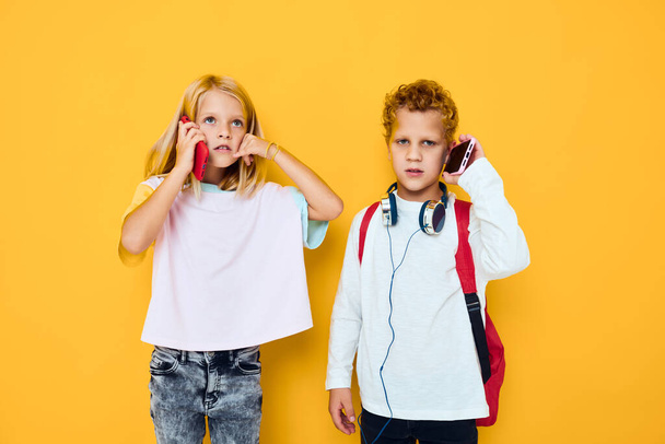 Dwoje dzieci chłopiec i dziewczyna ze szkolnymi plecakami telefon rozrywki komunikacji - Zdjęcie, obraz