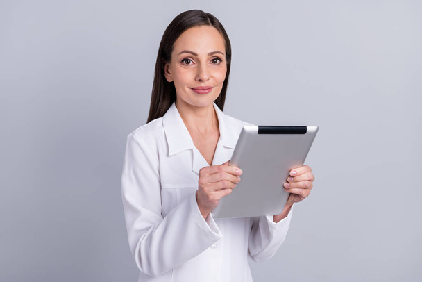 Portrait of attractive skilled nurse doctor using tablet reading medical web doc isolated over grey pastel color background - Fotoğraf, Görsel