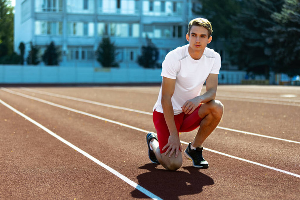 Young Caucasian sportive man, male athlete, runner practicing alone at public stadium, sport court or running track outdoors. Summer sport games. - Fotografie, Obrázek