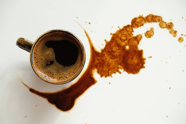 Cup of espresso on spilled coffee spots on white background, top view - Photo, Image