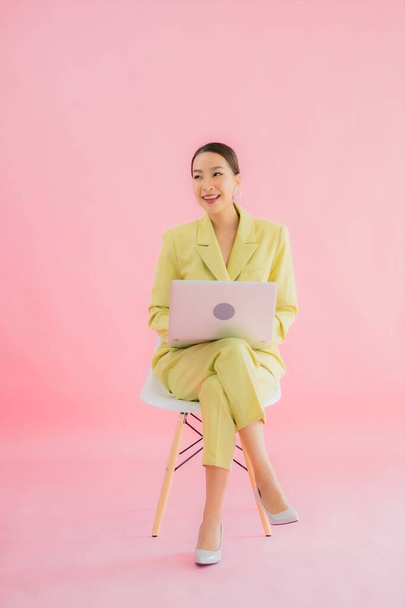 Portré gyönyörű fiatal ázsiai üzleti nő használja számítógép laptop színes háttér - Fotó, kép