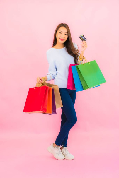 Retrato hermosa joven mujer asiática con colorido bolso de compras en color rosa aislado fondo - Foto, Imagen