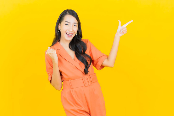 Portrét krásná mladá asijská žena úsměv s akcí na žlutém pozadí - Fotografie, Obrázek